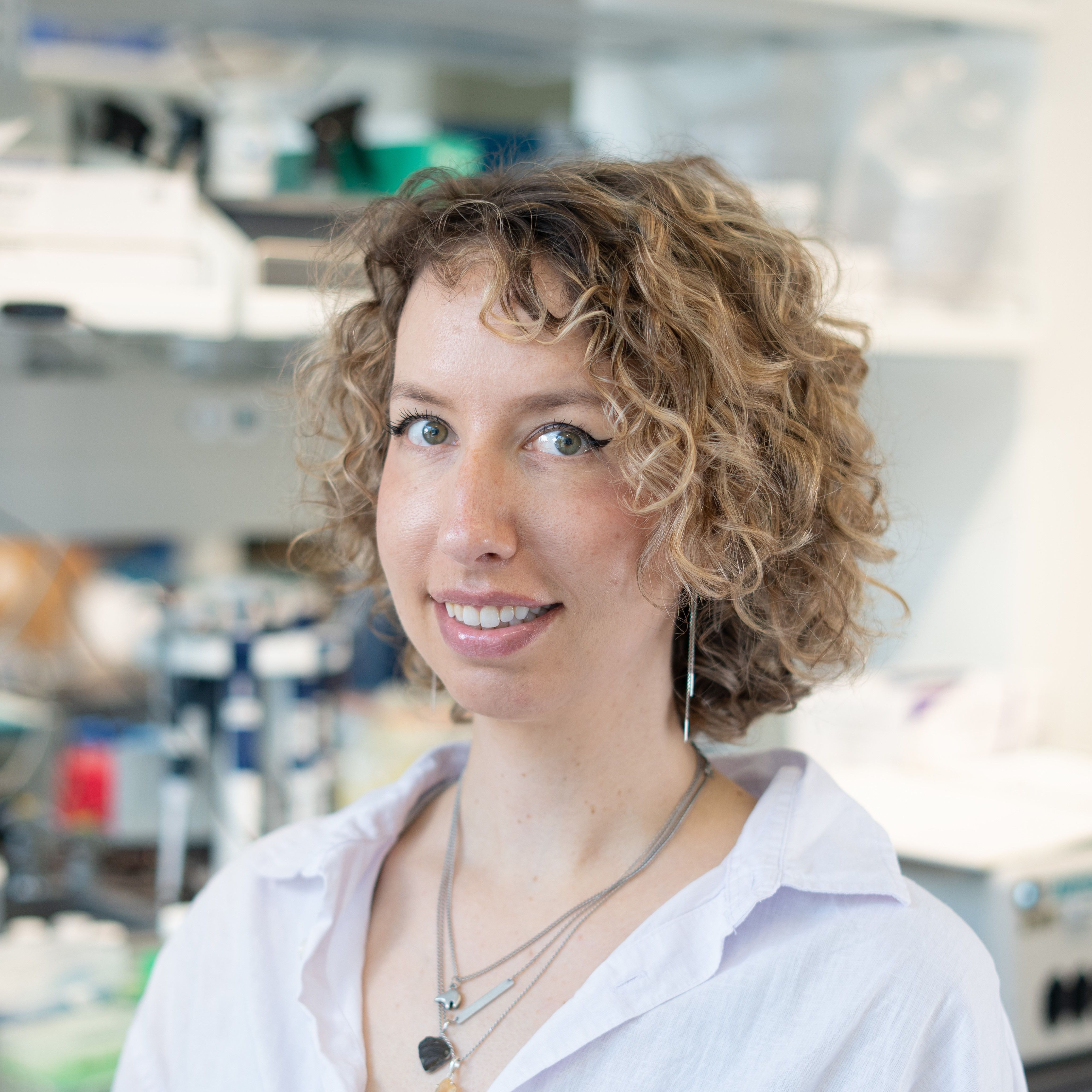 Woman with short curly light brown hair in a lab