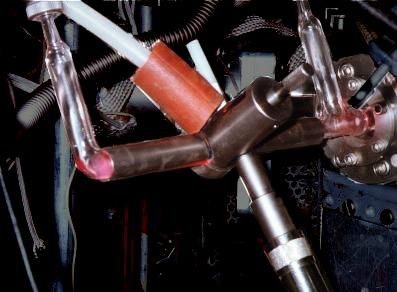 Metal pipes encasing portions of glass tubes emitting a red glow.